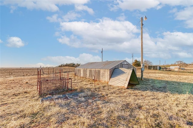 view of outbuilding featuring fence, an outbuilding, and a rural view