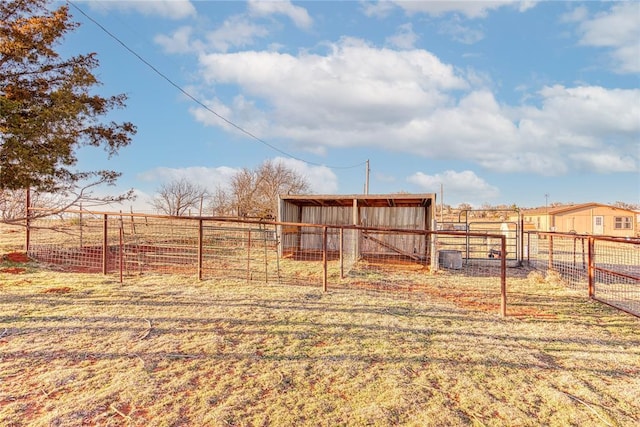 view of yard featuring a rural view, fence, and an outbuilding