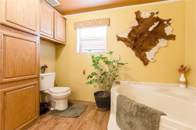 bathroom with wood finished floors, visible vents, toilet, and a bath