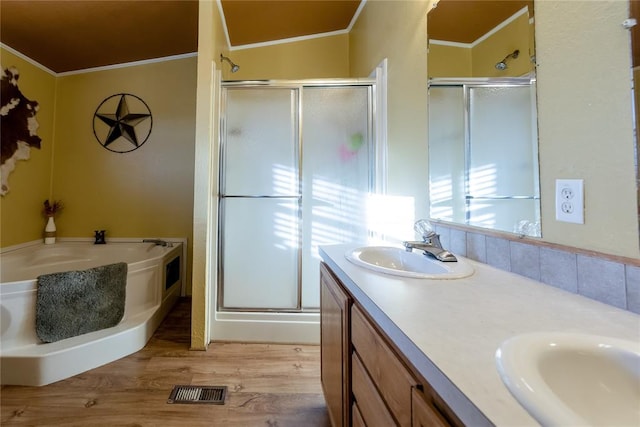 bathroom featuring wood finished floors, ornamental molding, a stall shower, and a sink