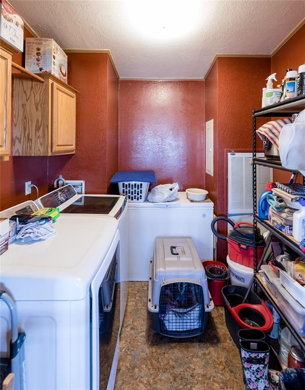 clothes washing area with cabinet space, stone finish floor, a textured ceiling, and independent washer and dryer