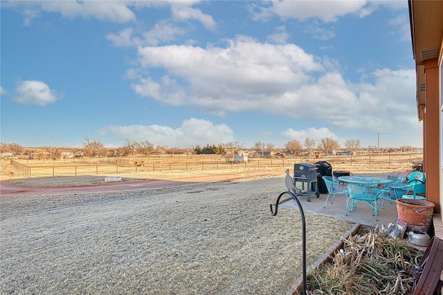 view of yard featuring a patio area, fence, and a rural view