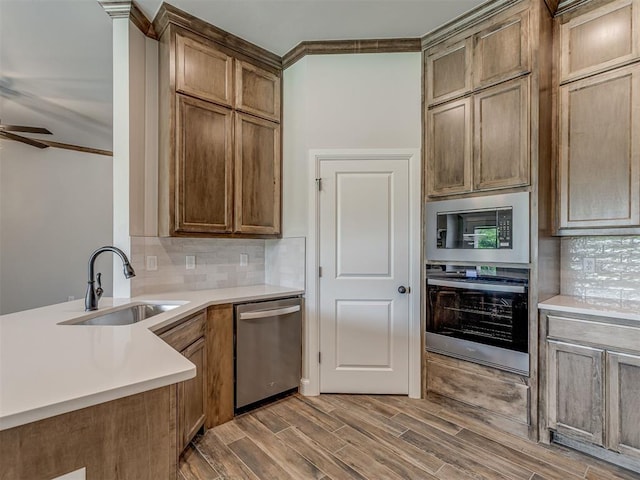 10124 Gentry Xing, Oklahoma City, OK 73169 - kitchen featuring appliances with stainless steel finishes, crown molding, tasteful backsplash, a ceiling fan, and wood finished floors