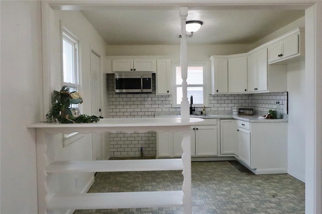 kitchen with stainless steel microwave, a sink, and white cabinetry