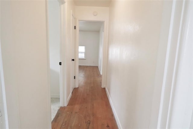 hallway featuring light wood finished floors and baseboards