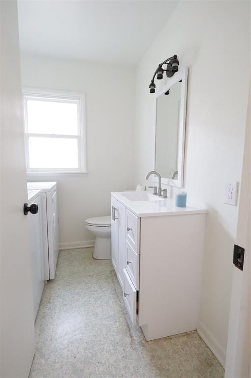 bathroom with toilet, vanity, baseboards, and washing machine and clothes dryer