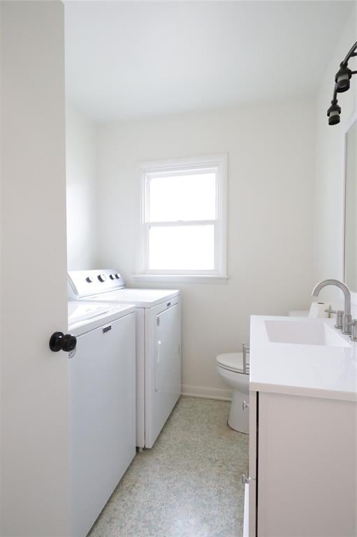 clothes washing area with laundry area, baseboards, a sink, and independent washer and dryer