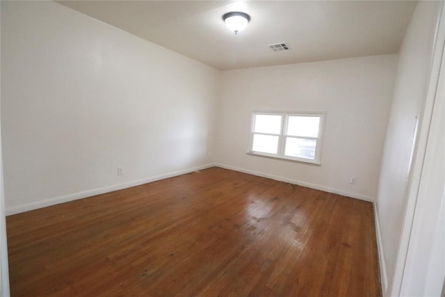 unfurnished room with baseboards, visible vents, and hardwood / wood-style floors