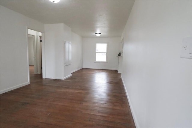 spare room with dark wood-style flooring and baseboards