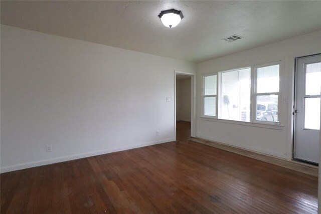 spare room featuring baseboards, visible vents, and wood finished floors