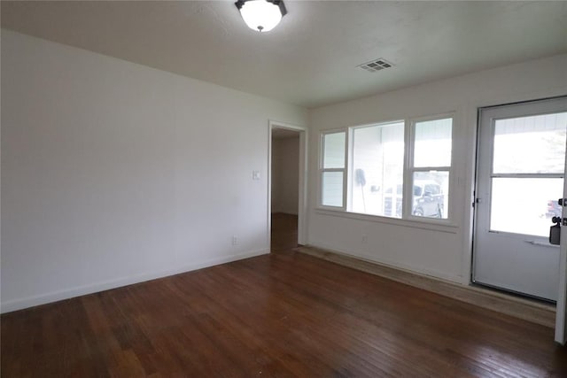 empty room featuring baseboards, visible vents, and wood finished floors