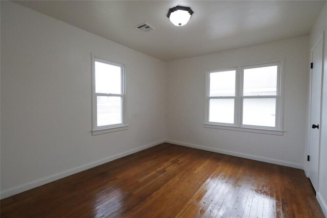 unfurnished room featuring hardwood / wood-style flooring, visible vents, and baseboards