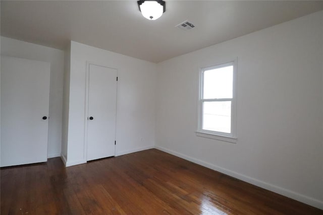 unfurnished bedroom featuring a closet, wood finished floors, visible vents, and baseboards