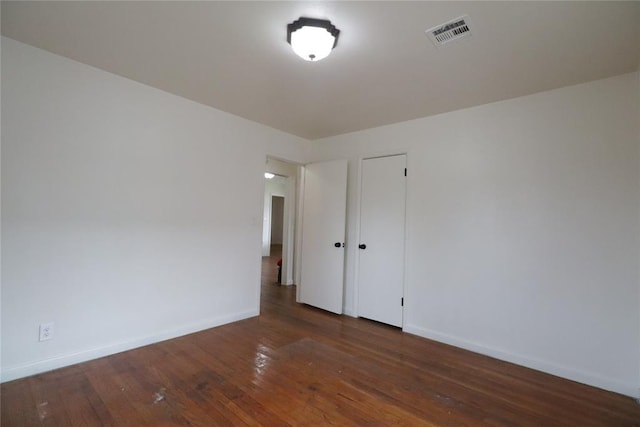 spare room with baseboards, visible vents, and hardwood / wood-style floors