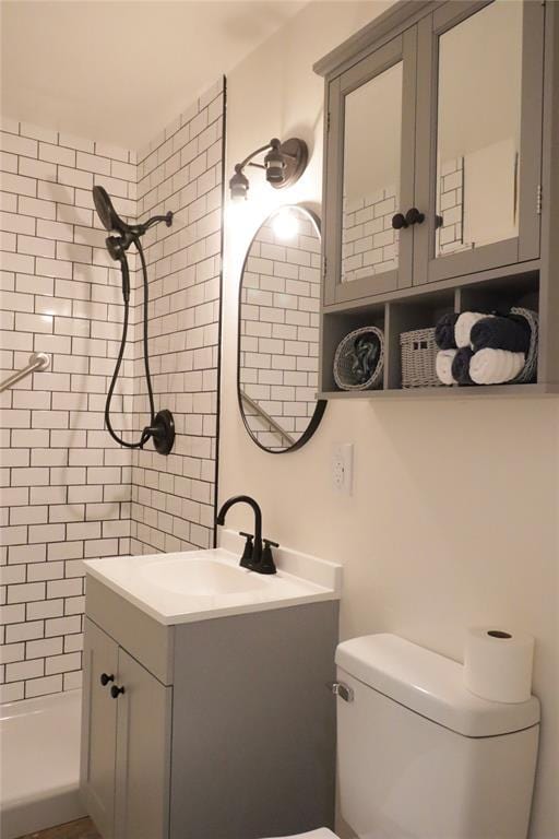 bathroom with vanity, a tile shower, and toilet