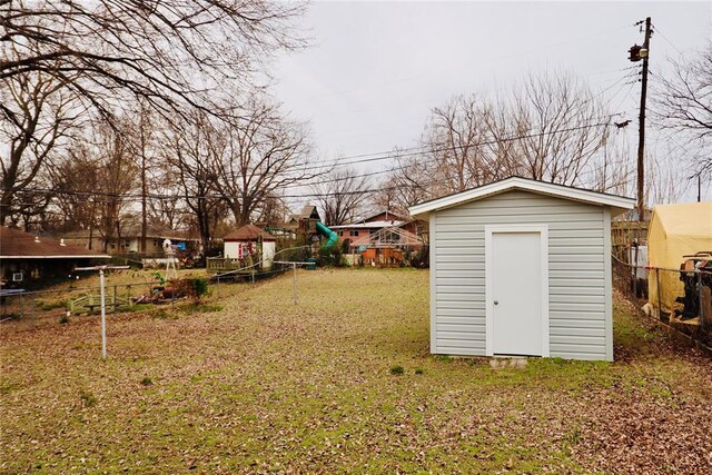 view of yard with a playground, a shed, an outdoor structure, and fence