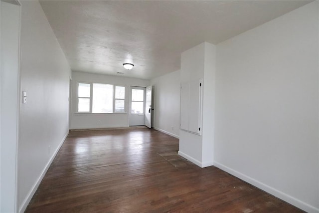 unfurnished room featuring baseboards and dark wood-style flooring