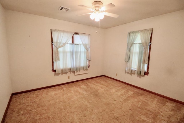 empty room with ceiling fan, carpet floors, visible vents, and baseboards