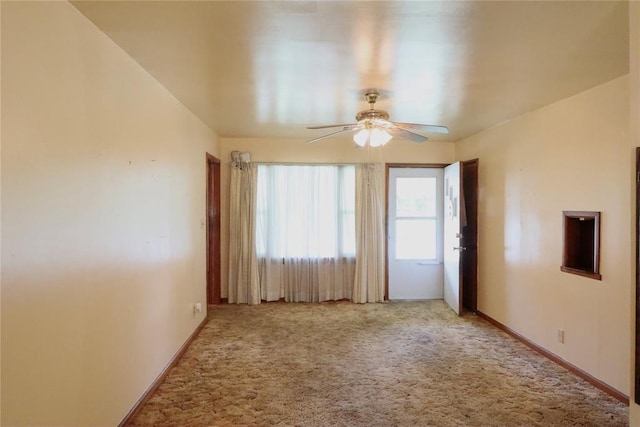 carpeted spare room with ceiling fan and baseboards