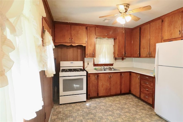 kitchen featuring ceiling fan, white appliances, a sink, light countertops, and brown cabinetry