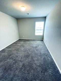 empty room featuring dark carpet and baseboards