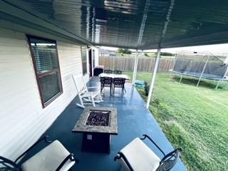 view of patio featuring a trampoline, an outdoor fire pit, fence, and outdoor dining space