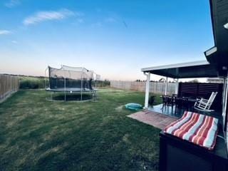 view of yard with a trampoline, a patio area, and a fenced backyard