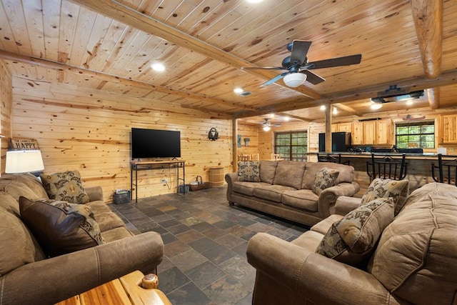 living room featuring stone tile floors, wood ceiling, ceiling fan, beamed ceiling, and wood walls