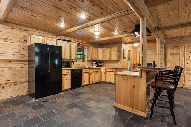 kitchen with light brown cabinets, wood walls, and black appliances