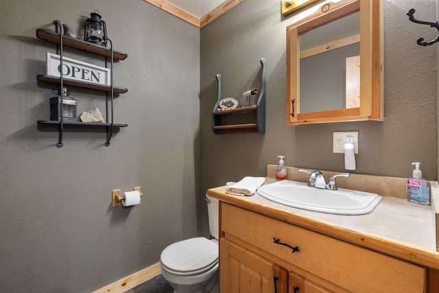 half bath featuring a textured wall, vanity, and toilet