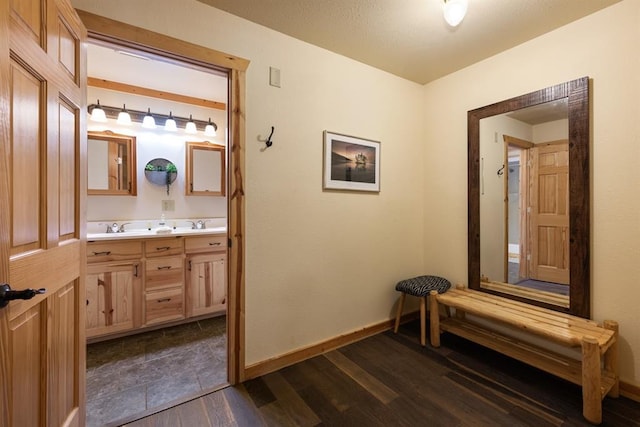 hallway featuring dark wood-style floors, baseboards, and a sink