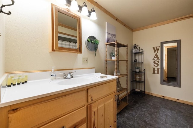 bathroom with stone finish floor, crown molding, vanity, and baseboards