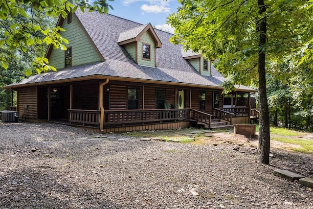 view of front of house with covered porch, a shingled roof, log veneer siding, and central AC unit