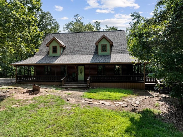 log-style house with a shingled roof, a porch, and a front yard