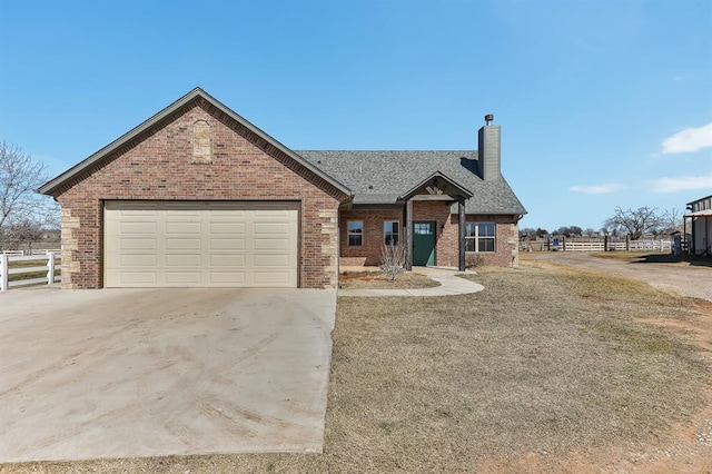 view of front facade with brick siding, a chimney, concrete driveway, fence, and a garage