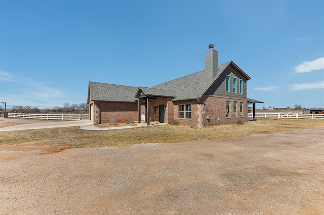 view of side of property featuring a chimney, fence, and brick siding