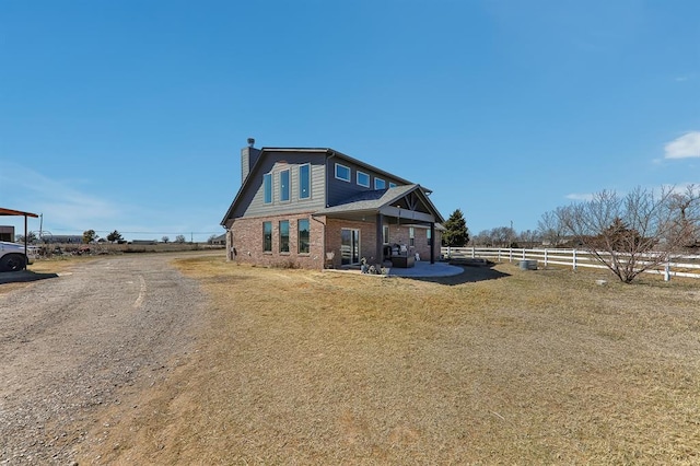 back of property featuring a patio, brick siding, fence, a yard, and a chimney