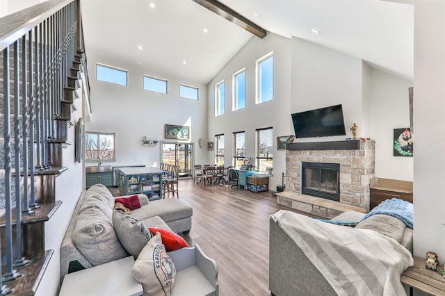 living area with wood finished floors, beamed ceiling, stairs, a fireplace, and recessed lighting