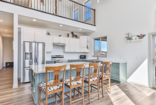 kitchen featuring stainless steel appliances, white cabinets, a sink, and light wood finished floors