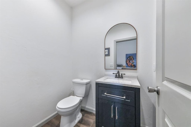 bathroom with wood finished floors, vanity, toilet, and baseboards