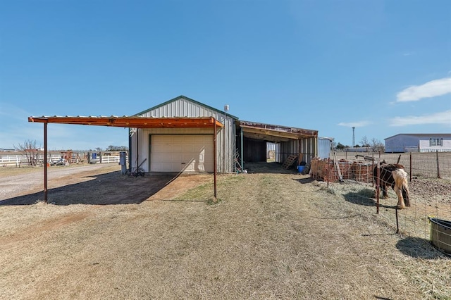 exterior space featuring a detached garage, fence, an outbuilding, and an outdoor structure