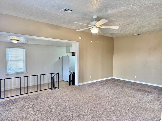 carpeted empty room featuring baseboards, visible vents, ceiling fan, and a textured ceiling