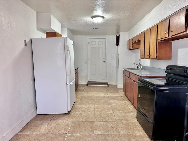 kitchen featuring visible vents, black electric range oven, freestanding refrigerator, a sink, and a textured ceiling