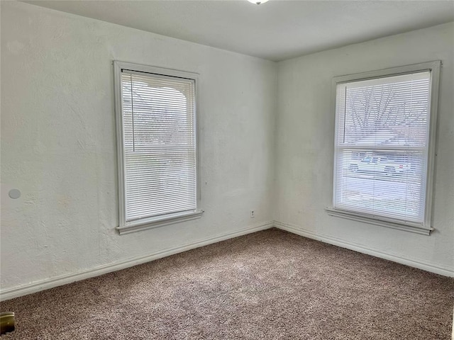 carpeted spare room with a textured wall and baseboards