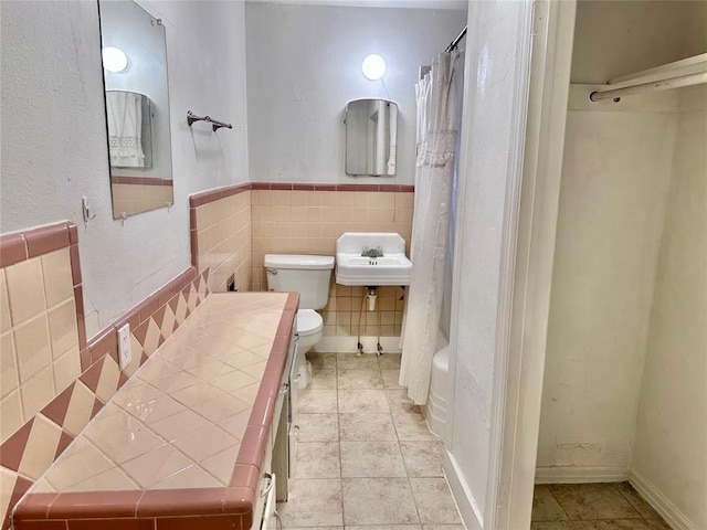 full bath with toilet, a shower with curtain, tile patterned flooring, and tile walls