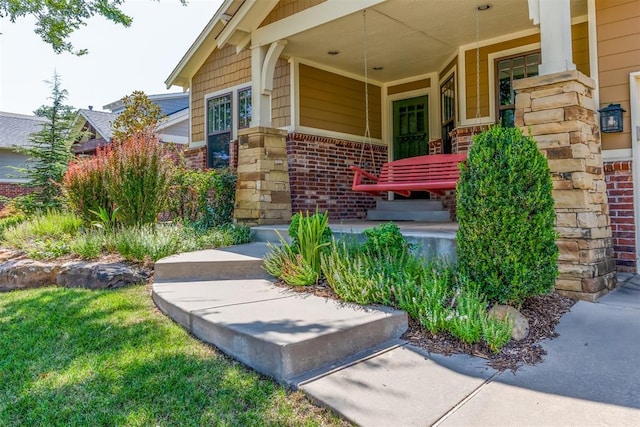 doorway to property featuring covered porch and brick siding