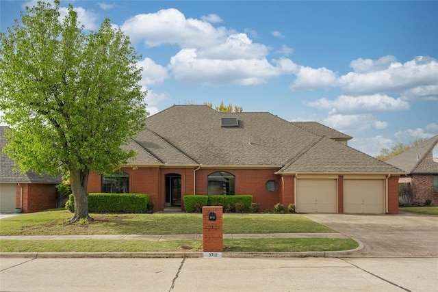 view of front of property with an attached garage, driveway, a front lawn, and brick siding
