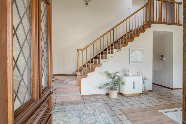 entrance foyer featuring tile patterned floors, stairway, and baseboards