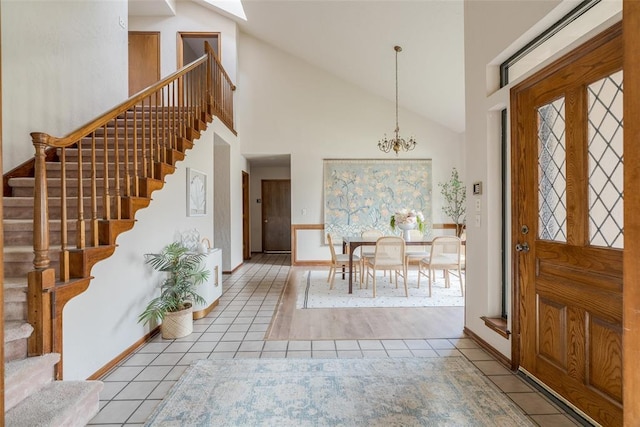 tiled entryway featuring high vaulted ceiling, stairway, baseboards, and an inviting chandelier