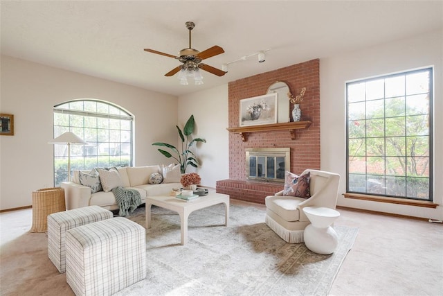living area featuring track lighting, ceiling fan, a fireplace, and carpet floors